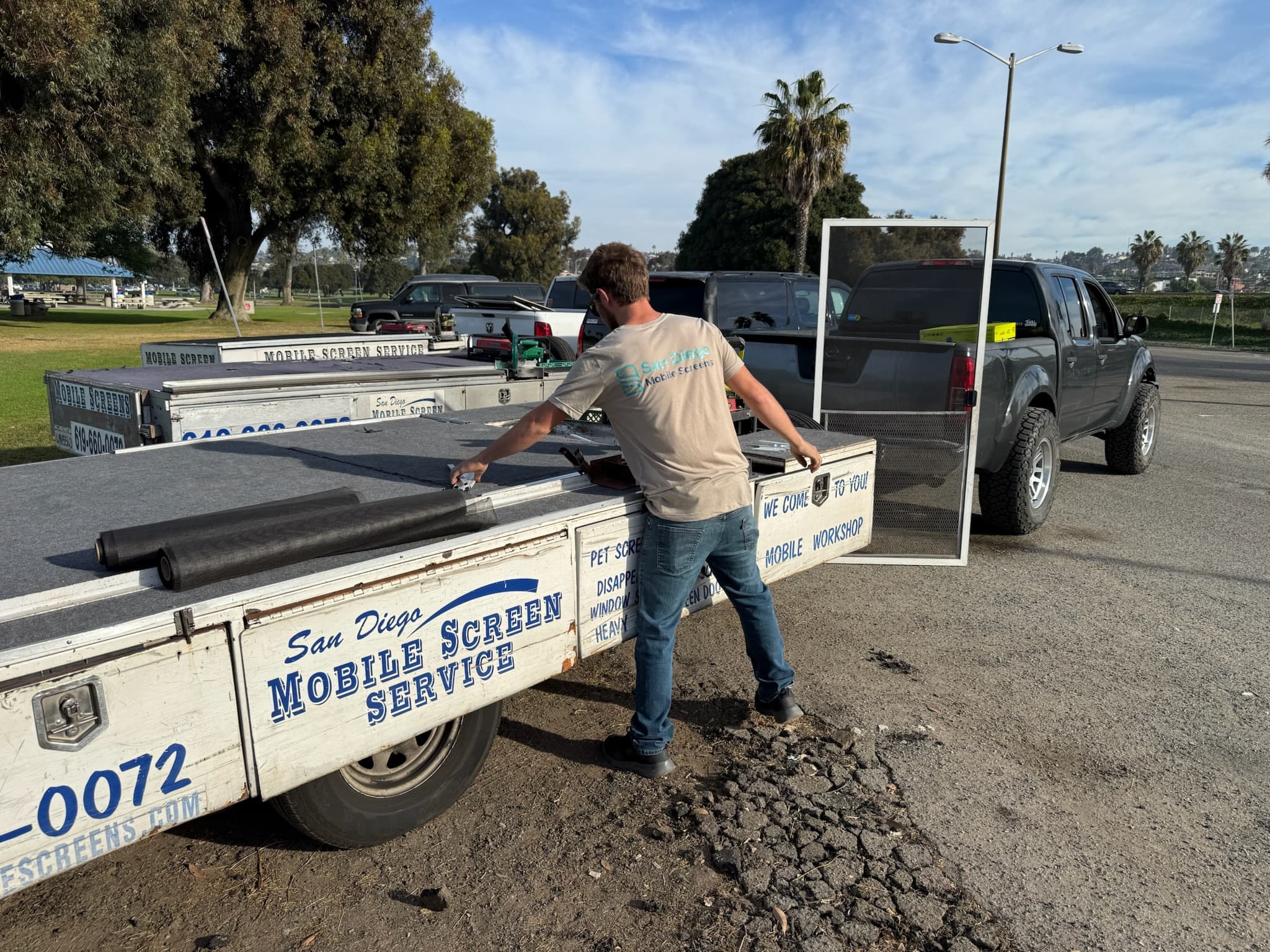 Technician loading a screen frame onto the mobile workshop trailer